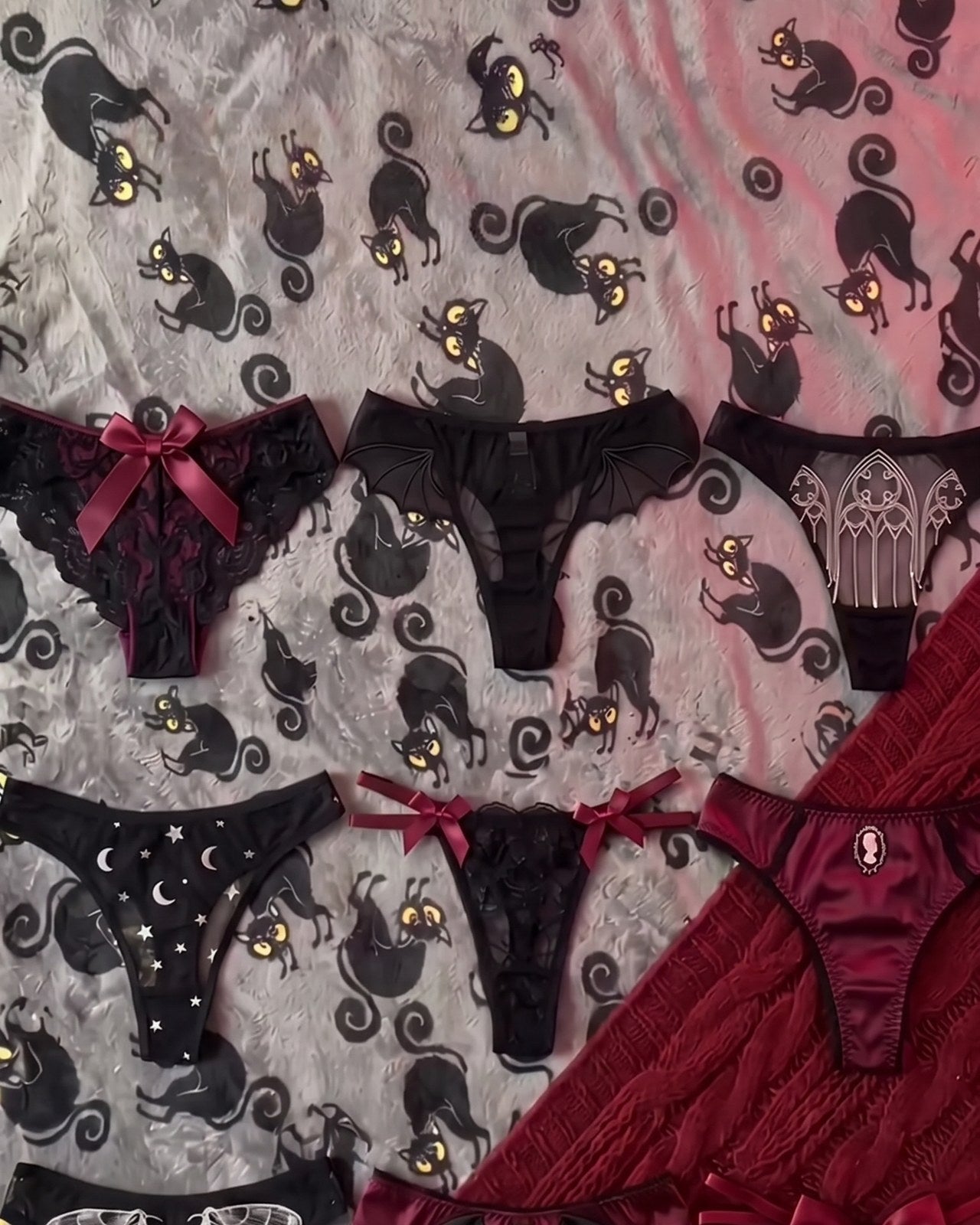 Goth thongs laid out on black cat sheets: lace, satin, bows and moons